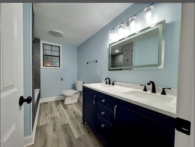 bathroom featuring wood-type flooring, toilet, vanity, and walk in shower