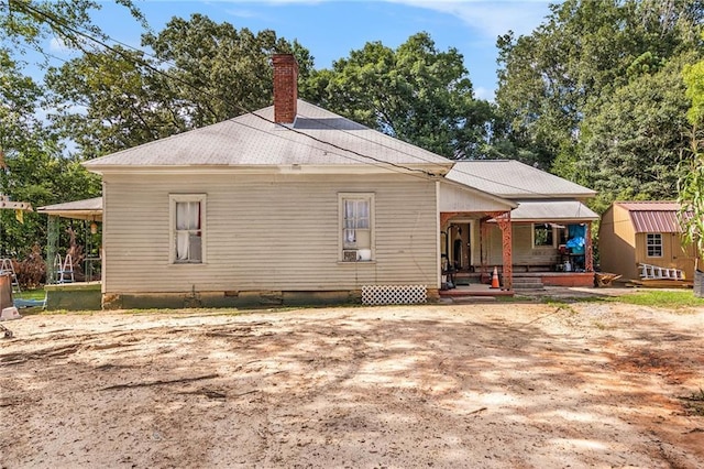 back of property featuring a porch and a shed