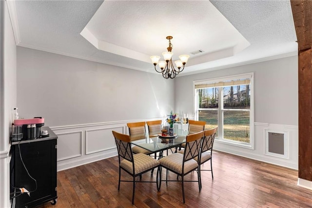 dining room with a tray ceiling, dark wood-type flooring, a chandelier, and a textured ceiling