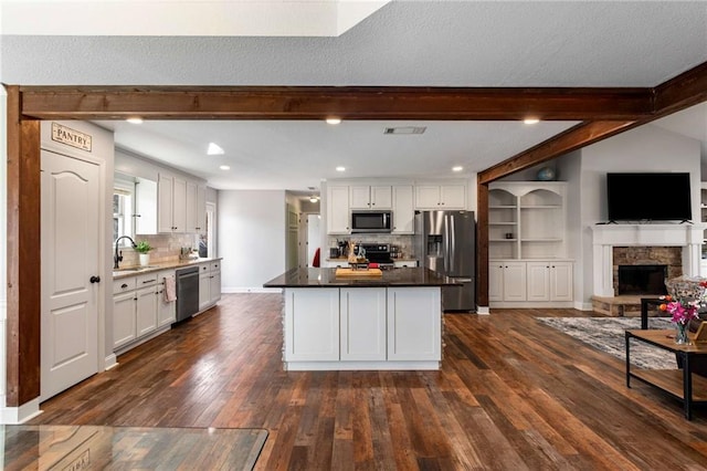 kitchen with visible vents, a sink, open floor plan, white cabinetry, and stainless steel appliances