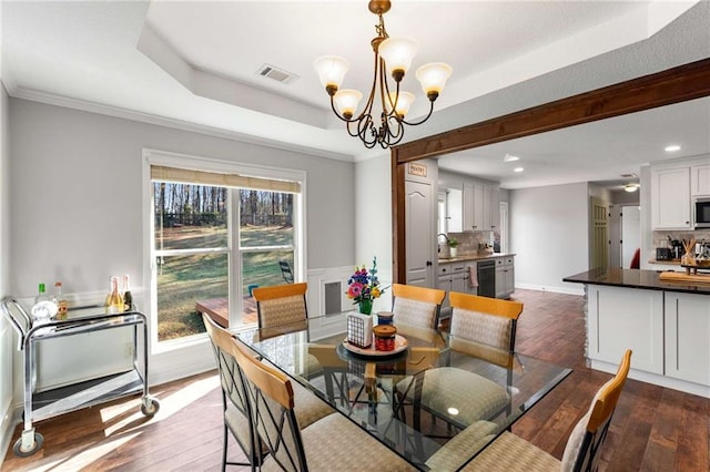 dining room with dark wood finished floors, a tray ceiling, crown molding, and a chandelier