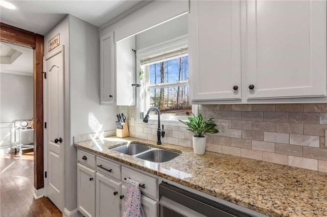 kitchen with decorative backsplash, white cabinets, and a sink