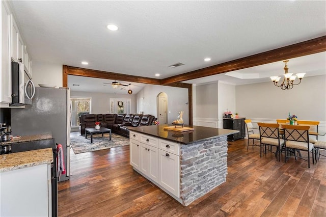 kitchen featuring stainless steel microwave, beam ceiling, dark wood-type flooring, and visible vents