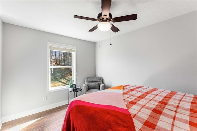 bedroom with baseboards, wood finished floors, and a ceiling fan