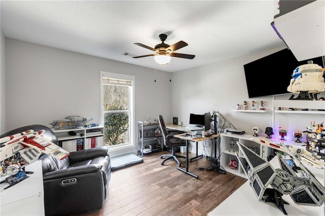 home office with visible vents, a textured ceiling, ceiling fan, and wood finished floors