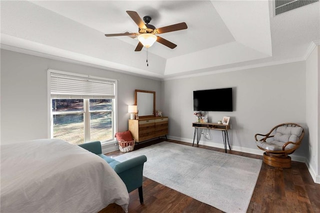 bedroom with a tray ceiling, wood finished floors, baseboards, and visible vents