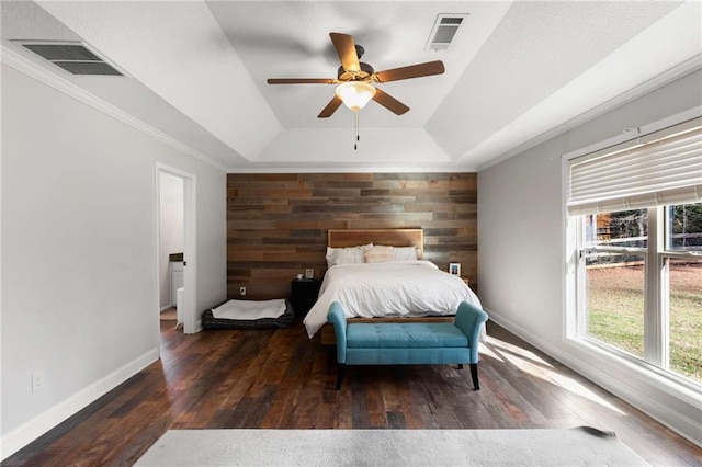 bedroom featuring visible vents, an accent wall, and wood-type flooring