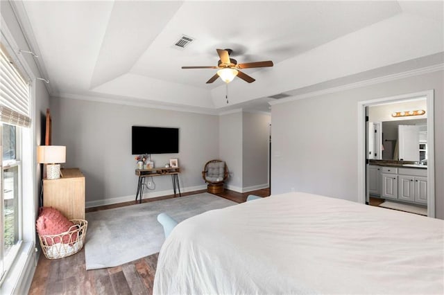 bedroom featuring a raised ceiling, wood finished floors, visible vents, and baseboards