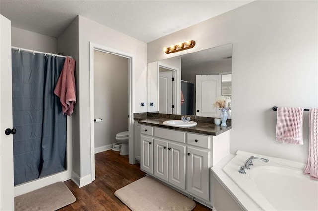 full bathroom featuring curtained shower, toilet, a garden tub, wood finished floors, and vanity