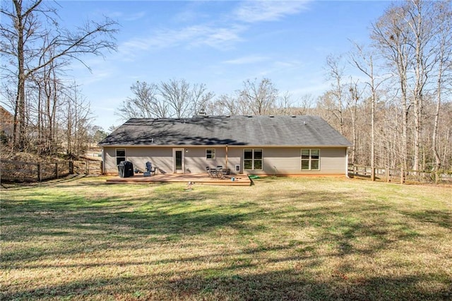 rear view of property with a wooden deck, a lawn, and fence