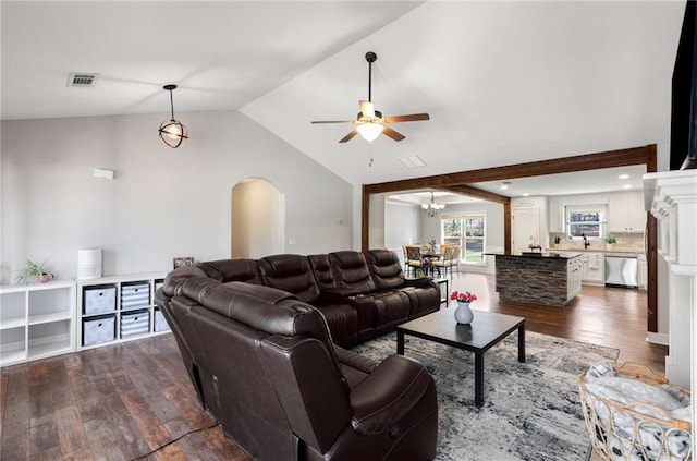 living room with visible vents, vaulted ceiling, ceiling fan with notable chandelier, arched walkways, and dark wood-style floors