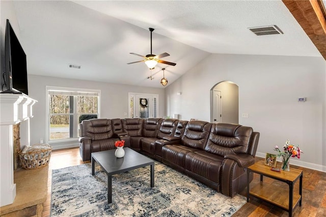 living room with visible vents, arched walkways, lofted ceiling, and wood finished floors