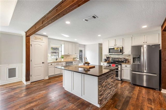 kitchen with dark wood-style floors, visible vents, appliances with stainless steel finishes, and white cabinetry