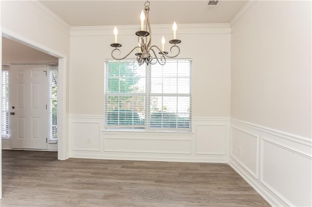 unfurnished dining area featuring ornamental molding, a chandelier, and hardwood / wood-style flooring