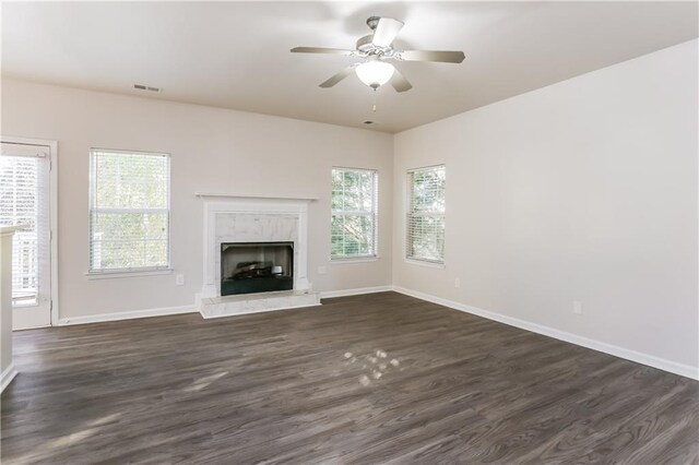 unfurnished living room with dark hardwood / wood-style flooring, a high end fireplace, and a healthy amount of sunlight