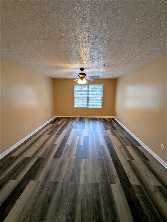 unfurnished room with dark wood finished floors, a ceiling fan, baseboards, and a textured ceiling