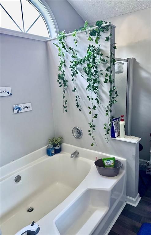 6030 Creekside Dr, Columbus, GA 31907 - bathroom with a textured ceiling, wood finished floors, and a garden tub