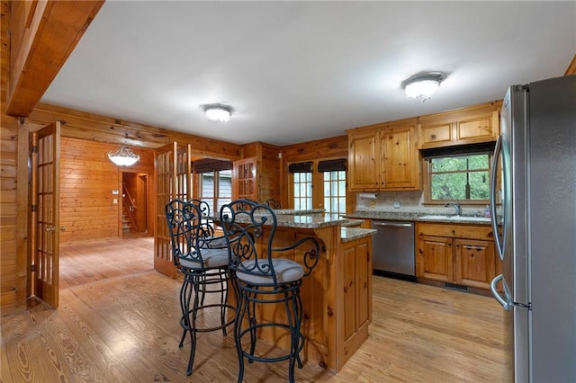 442 Cartecay River Run, Ellijay, GA 30536 - kitchen with appliances with stainless steel finishes, light wood-style flooring, a breakfast bar area, light stone countertops, and wooden walls