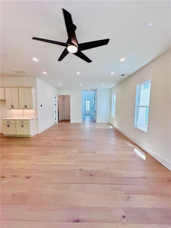 unfurnished living room with visible vents, light wood-style flooring, a ceiling fan, recessed lighting, and baseboards