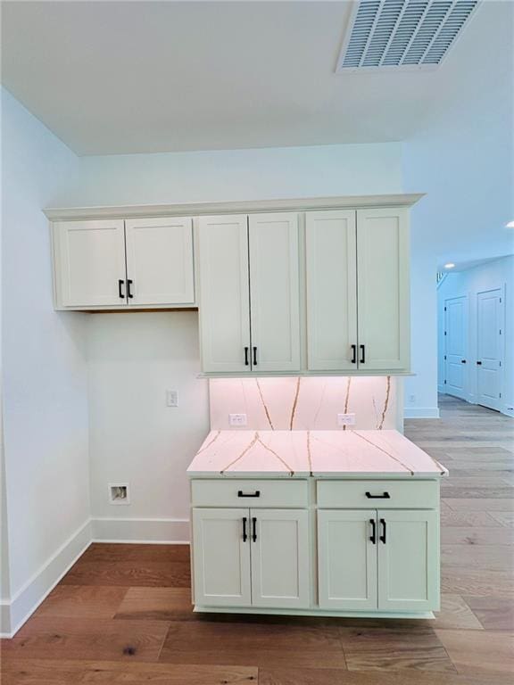 clothes washing area featuring visible vents, baseboards, and light wood-style flooring