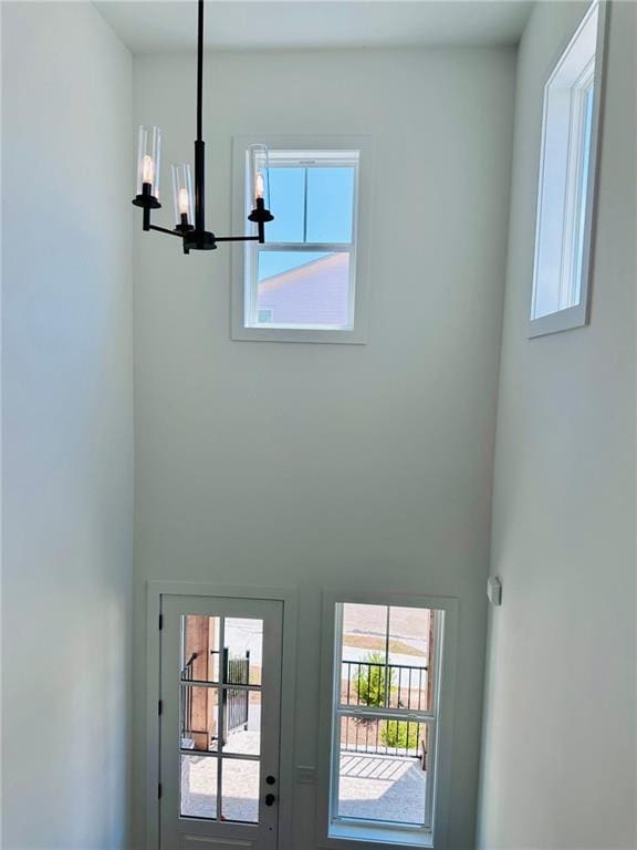 entrance foyer with a wealth of natural light, a high ceiling, and an inviting chandelier