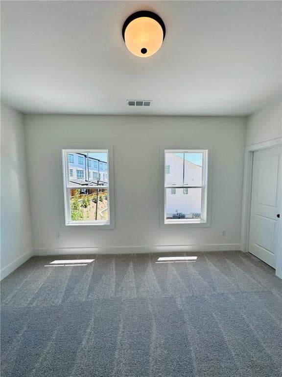 carpeted empty room with a wealth of natural light, visible vents, and baseboards