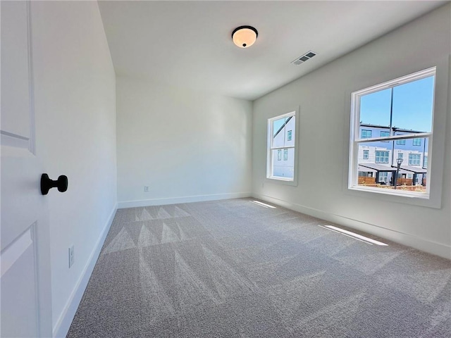 spare room featuring carpet flooring, baseboards, and visible vents