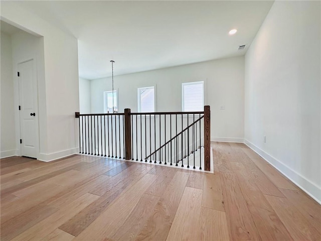 empty room with light wood-type flooring, visible vents, recessed lighting, baseboards, and a chandelier