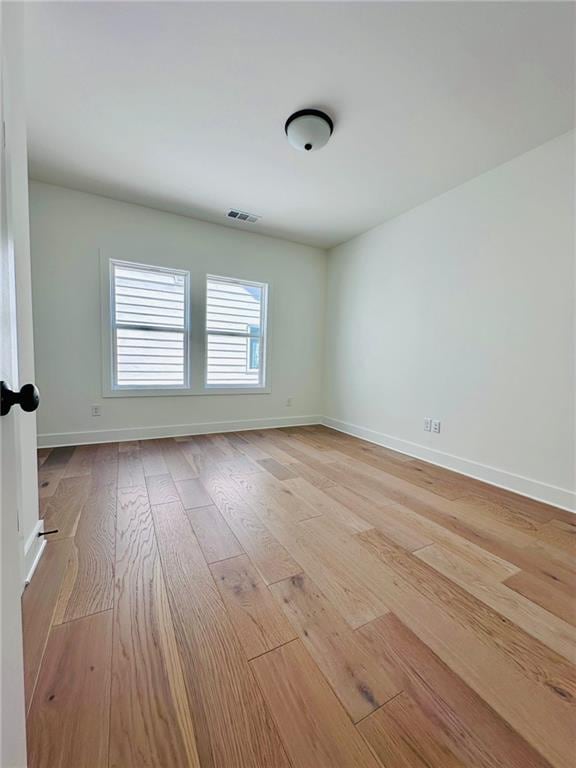 empty room with visible vents, baseboards, and light wood finished floors