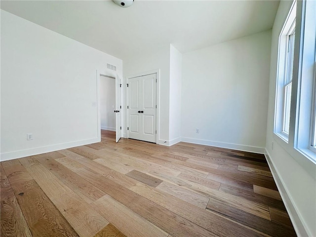 spare room with light wood-style flooring, baseboards, and visible vents