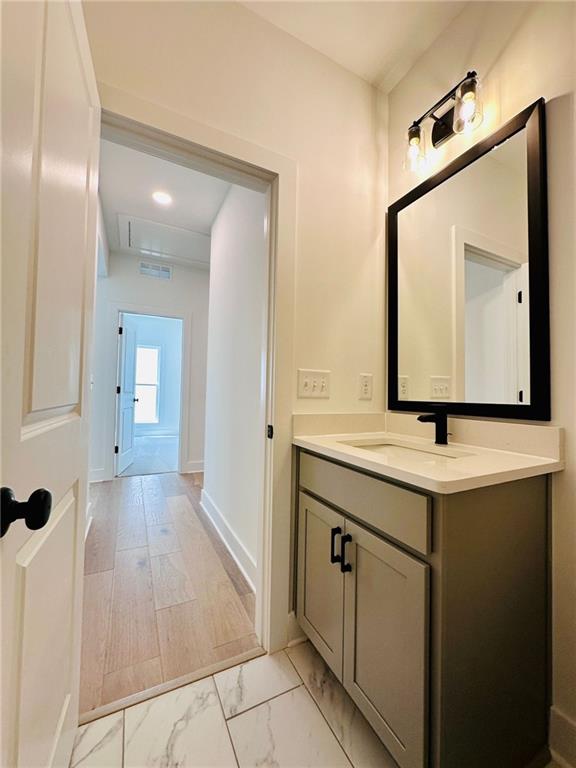 bathroom featuring vanity, visible vents, baseboards, and marble finish floor