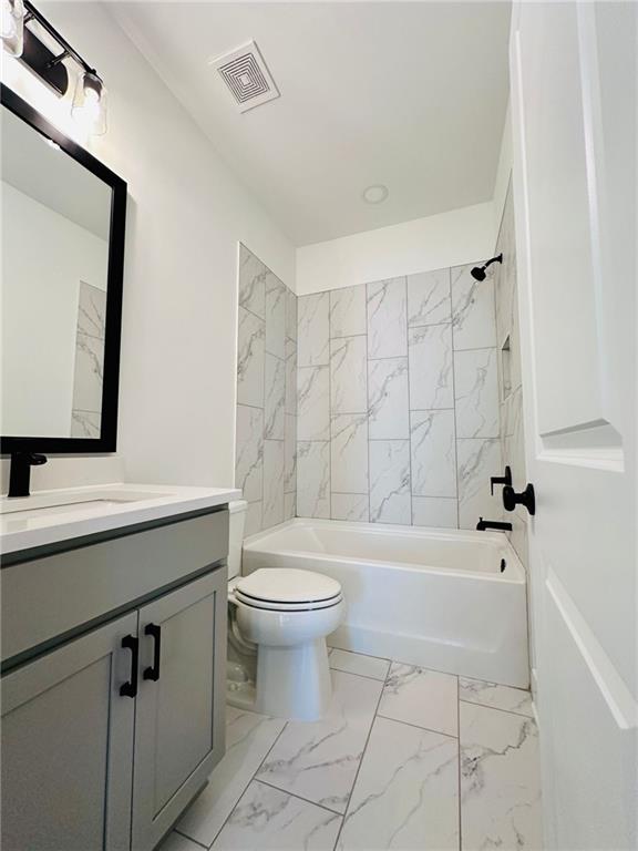 bathroom featuring visible vents, toilet, marble finish floor, shower / washtub combination, and vanity