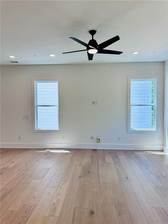 unfurnished room featuring baseboards, visible vents, light wood finished floors, and ceiling fan