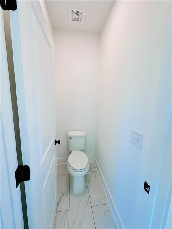 bathroom featuring toilet, visible vents, marble finish floor, and baseboards