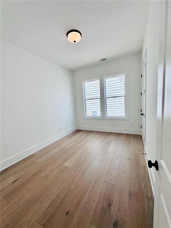 spare room with visible vents, light wood-style flooring, and baseboards