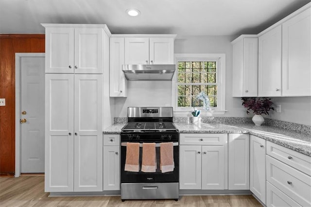 kitchen featuring stainless steel gas range oven, light stone countertops, white cabinetry, and under cabinet range hood