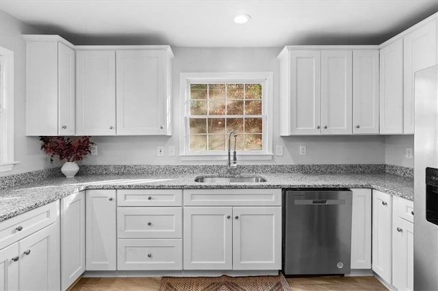 kitchen featuring a sink, white cabinetry, light stone counters, and stainless steel dishwasher