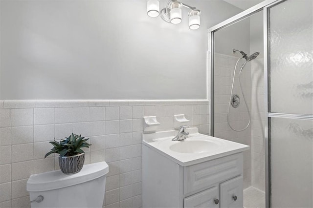 full bathroom featuring tile walls, toilet, wainscoting, a shower stall, and vanity