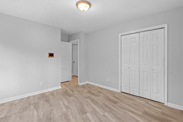 unfurnished bedroom with light wood-style floors, baseboards, and a closet