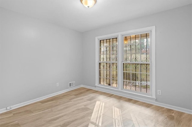 unfurnished room with light wood-type flooring, visible vents, and baseboards