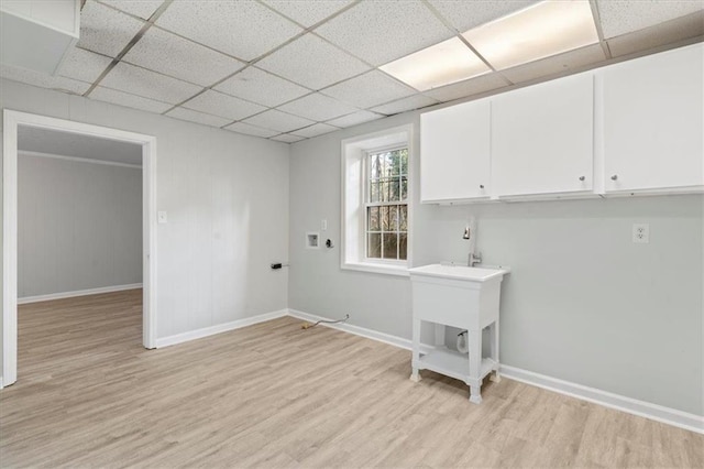 washroom with light wood-style flooring, cabinet space, and baseboards