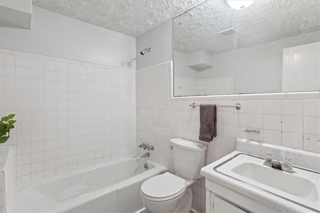 bathroom featuring a textured ceiling, toilet, vanity, tile walls, and washtub / shower combination