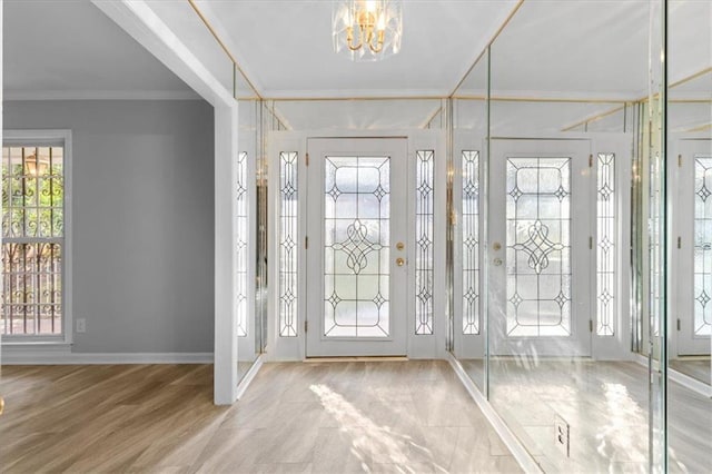 entrance foyer with baseboards, ornamental molding, and an inviting chandelier