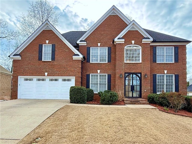 colonial-style house featuring brick siding, driveway, an attached garage, and french doors