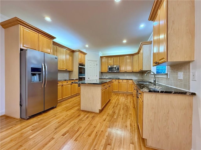 kitchen with sink, light hardwood / wood-style flooring, dark stone countertops, a kitchen island, and stainless steel appliances