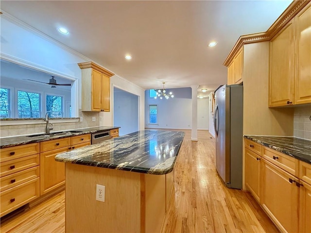 kitchen with stainless steel appliances, a center island, sink, and dark stone countertops