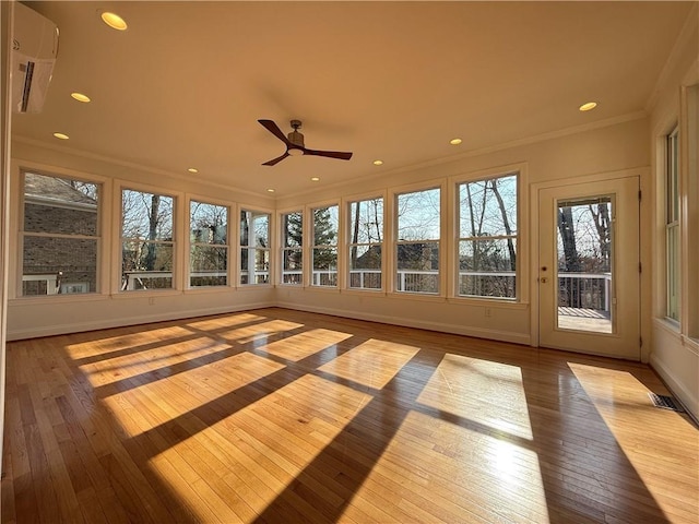 unfurnished sunroom featuring a wall mounted air conditioner and ceiling fan