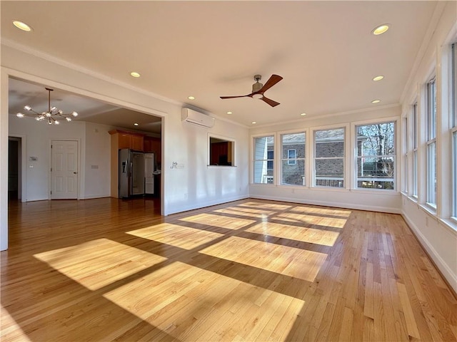 unfurnished living room with crown molding, ceiling fan with notable chandelier, a wall unit AC, and light wood-type flooring