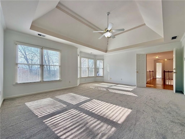 carpeted spare room with a raised ceiling, crown molding, and ceiling fan