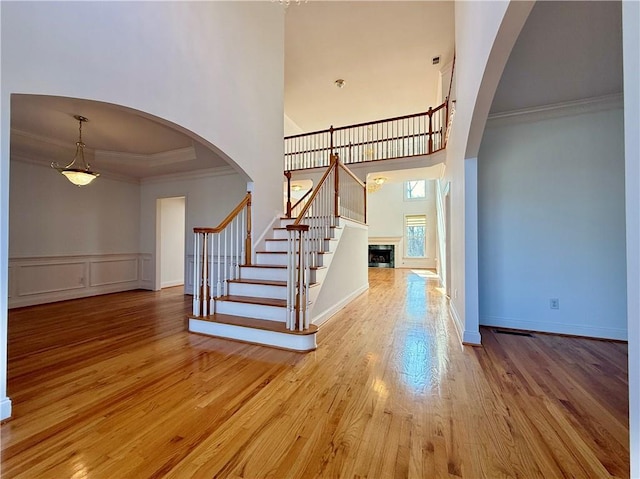 foyer with crown molding, wood-type flooring, and a high ceiling